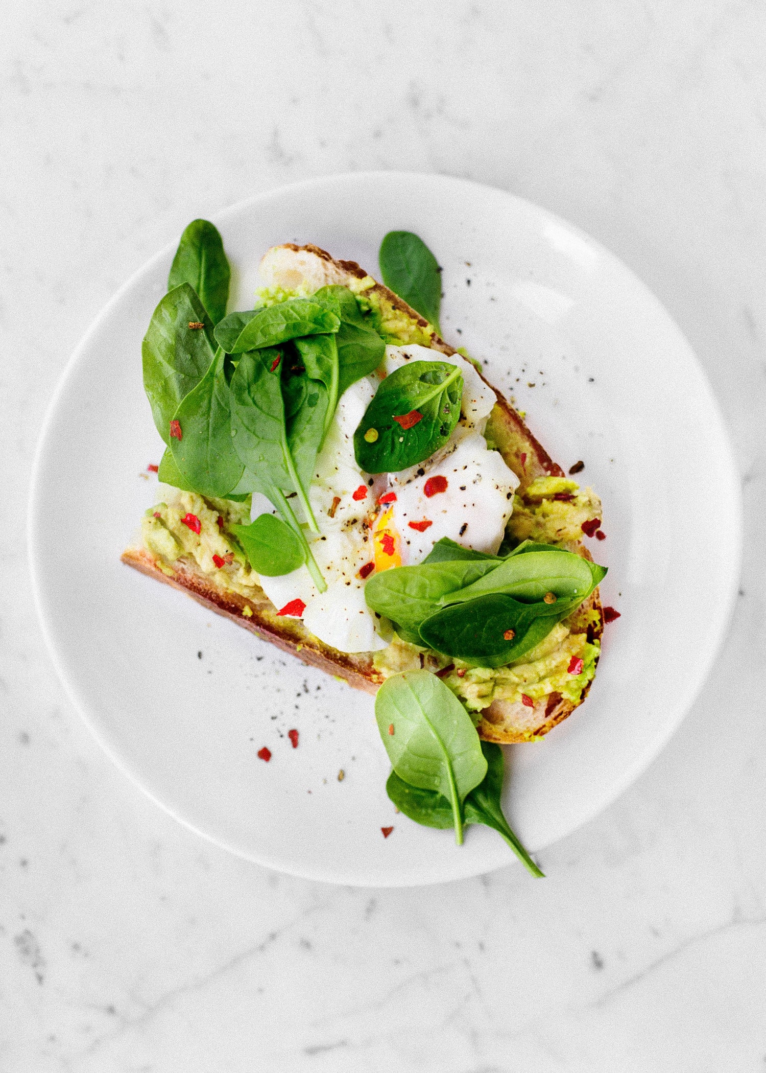 Perfekt gewürzte pochierte Eier mit Avocado und Sauerteigbrot, verfeinert mit frisch gemahlenem Pfeffer und Salz aus Iron-Mills Mühlen.