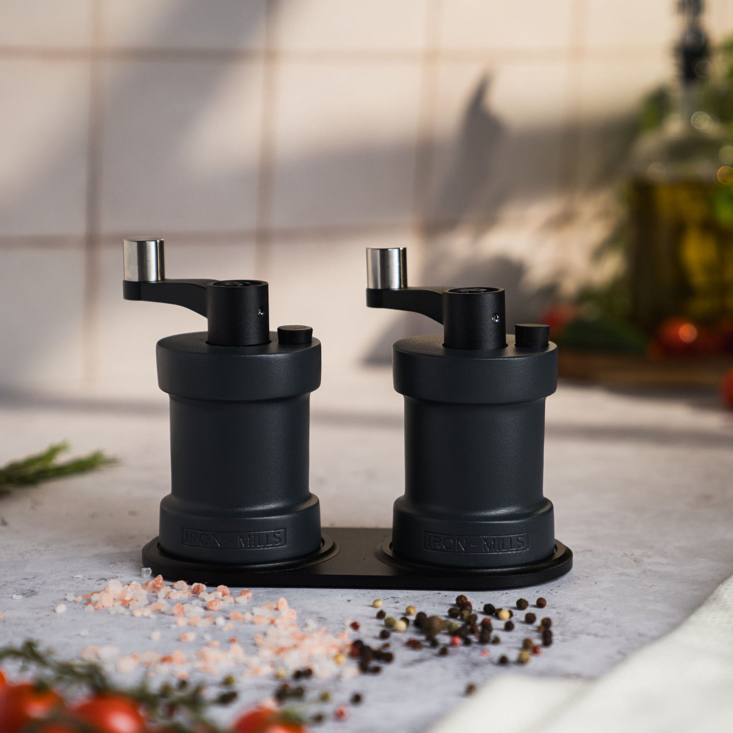 Iron-Mills anthracite grey salt and pepper mills displayed together on a premium mill rest in a sleek modern kitchen