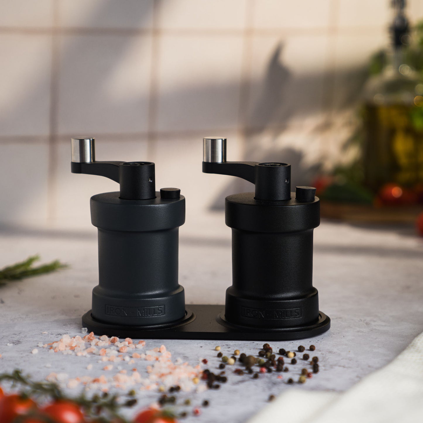 Iron-Mills anthracite grey and onyx black salt and pepper mills displayed on a premium mill rest in a modern kitchen