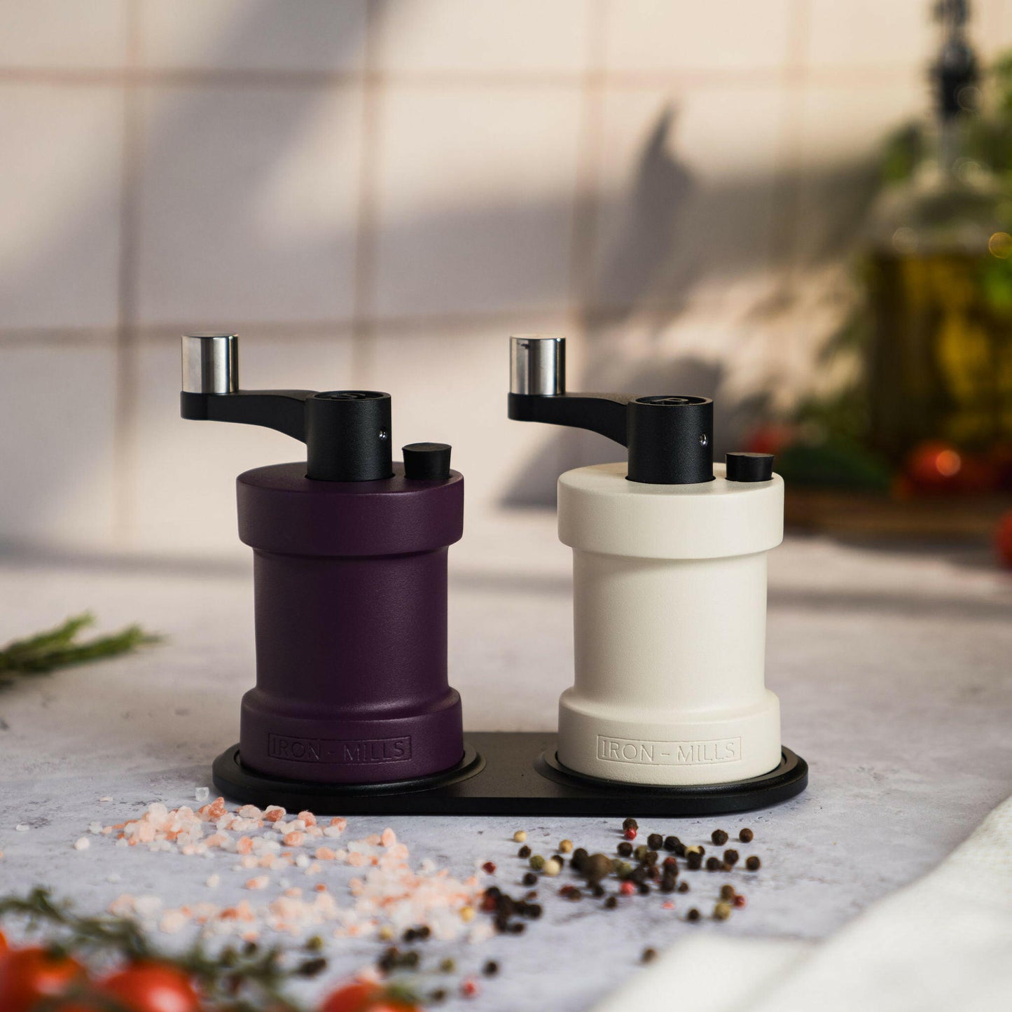 Iron-Mills oyster white and rich purple salt and pepper mills displayed on a mill rest for a touch of sophistication