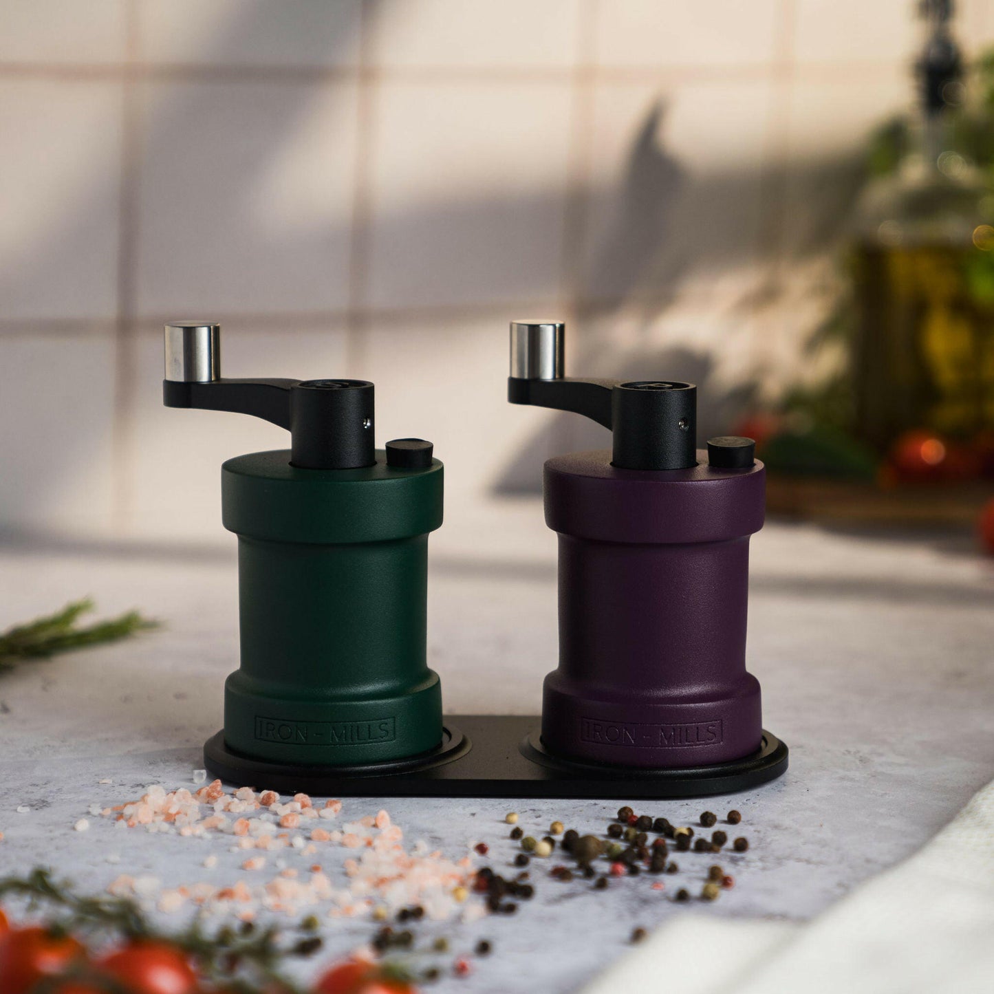 Iron-Mills deep purple and ivy green salt and pepper mills on a mill rest, adding a bold and earthy touch to the kitchen